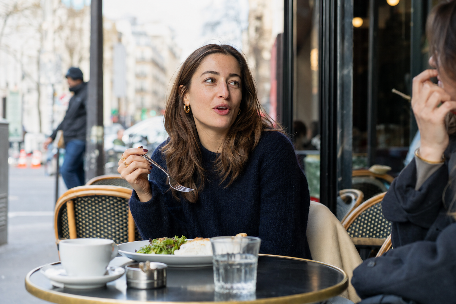 A French speaker at a Paris cafe terrace, mid-conversation over lunch
